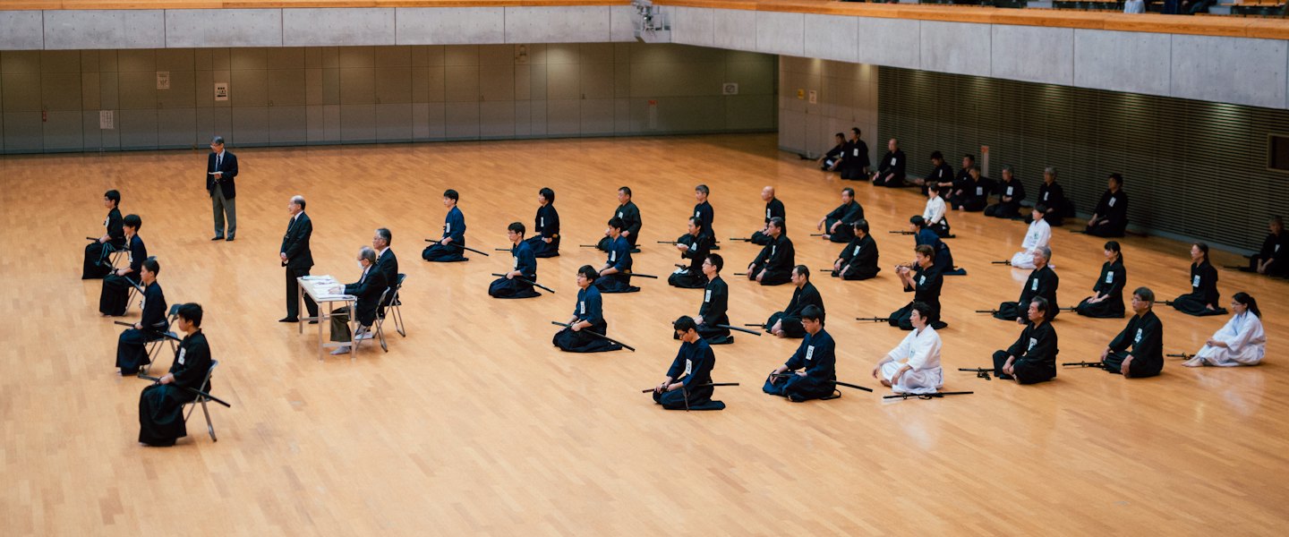 Persone in uniforme da arti marziali durante una cerimonia al chiuso.