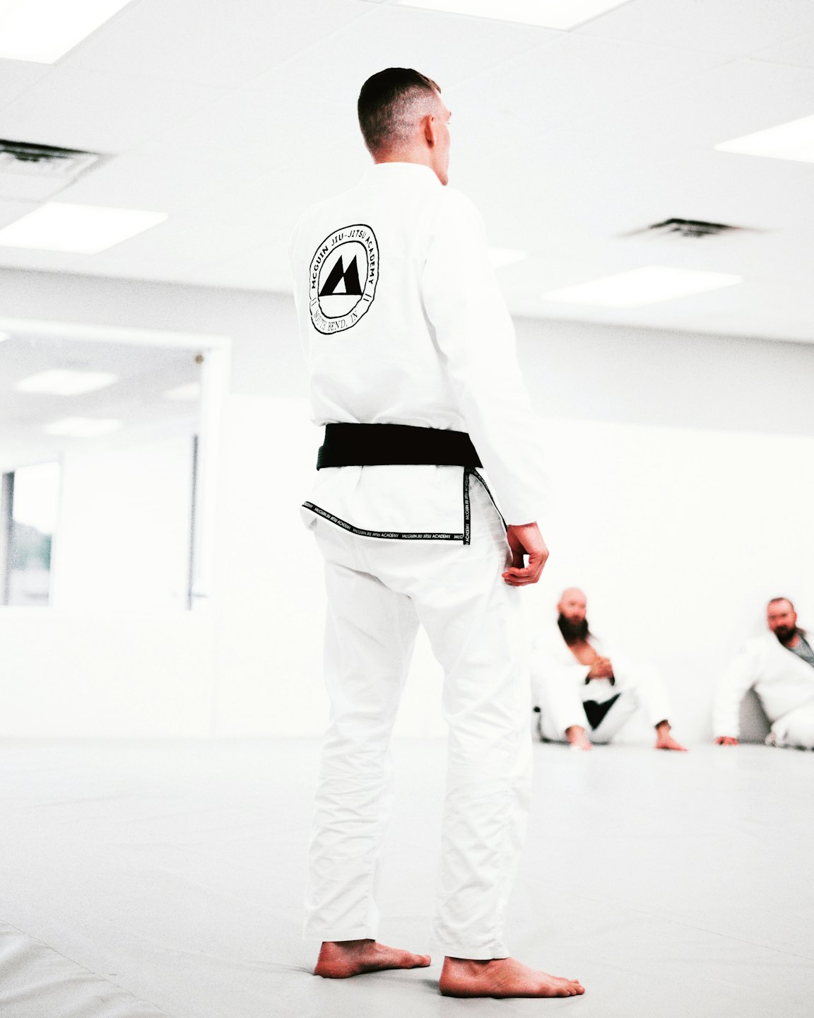 Un artista marziale in un kimono bianco con cintura nera in un dojo.