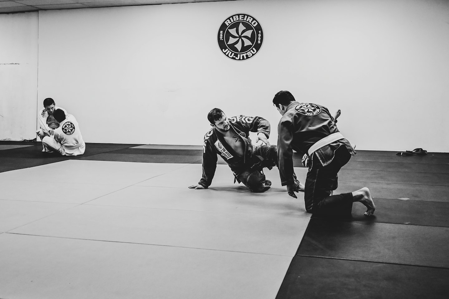 Quattro uomini praticano il Jiu-Jitsu brasiliano in un dojo.